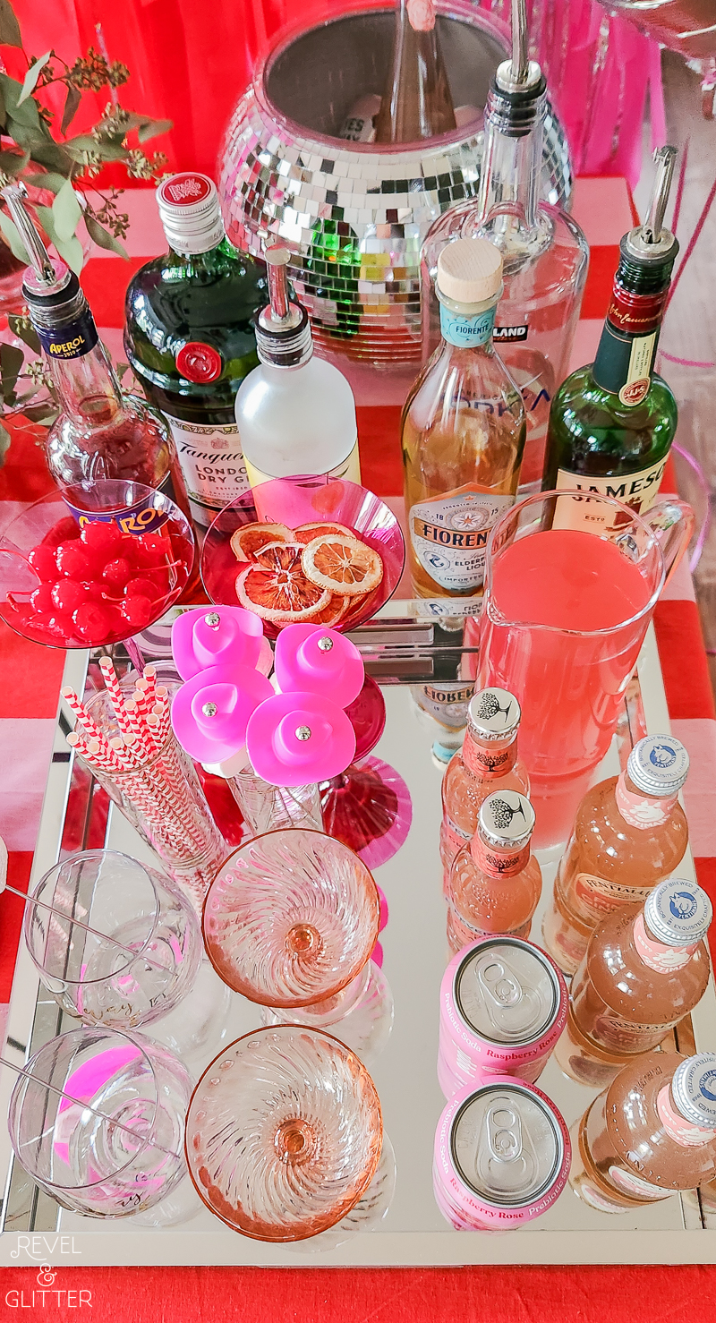 A tabletop drink bar on a mirrored tray featuring mini cowgirl hat stirrers
