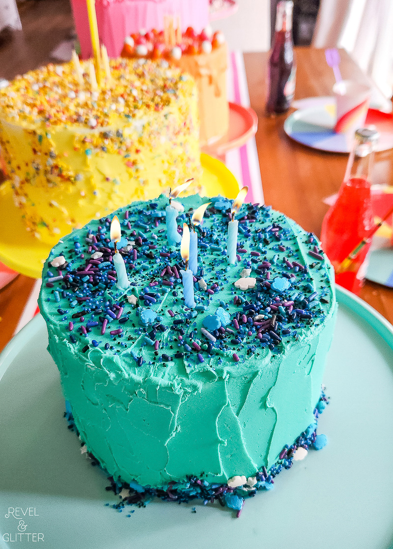 Close up view of blue frosted cake with candles, on a blue cake stand