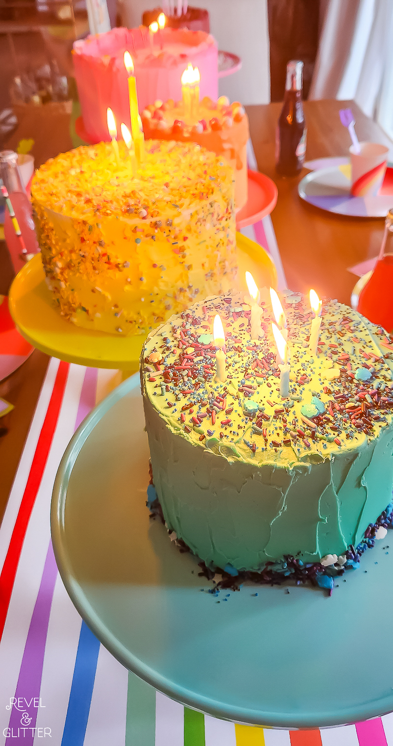 Close up of rainbow partyware and Rainbow Cakes on coordinating cake stands